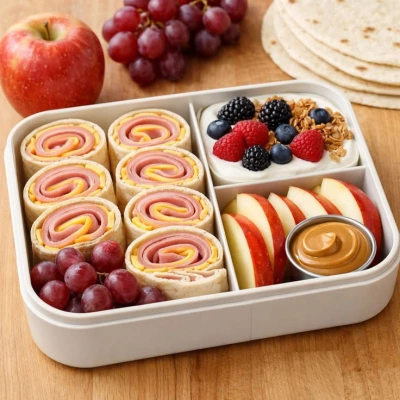 Lonchera con rollitos de jamón, manzana, yogur y uvas